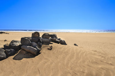 Scenic view of beach against clear blue sky
