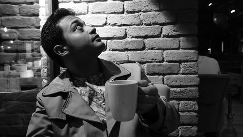 Portrait of young woman with coffee cup against wall