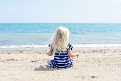 Rear view of girl sitting on beach