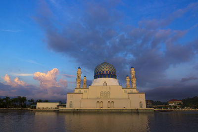 Cathedral by lake and buildings against sky