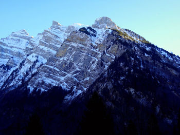 Low angle view of snowcapped mountains against blue sky