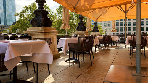 Empty chairs and tables in cafe against building