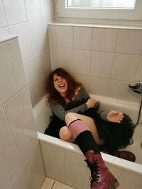 Portrait of young woman sitting on tiled floor at home