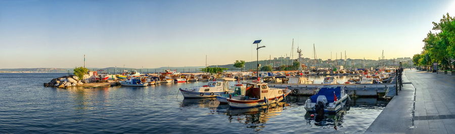 Boats moored in harbor against clear sky