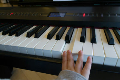 Close-up of hand playing piano