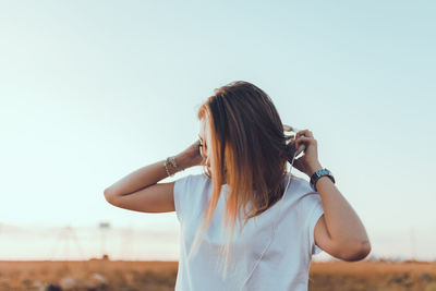 Woman standing against clear sky at sunset