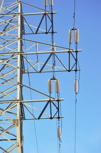 Low angle view of electricity pylon against clear blue sky