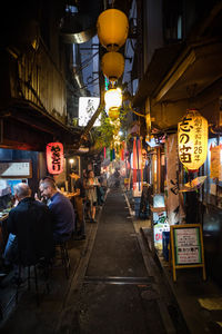 People on illuminated street market in city at night