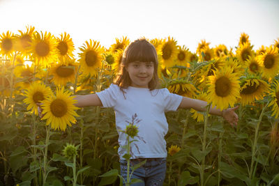 Portrait of girl with sunflower standing in background
