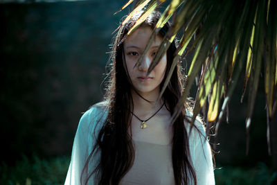 Portrait of young woman standing by plants