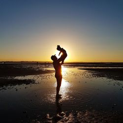 Silhouette man standing on beach against sky during sunset