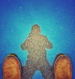 Low section of woman standing against blue sky