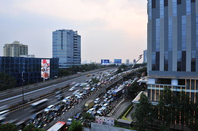 Road by buildings in city against sky