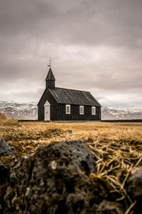 Chapel on field against cloudy sky