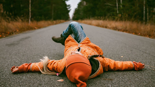 Girl lays on the road in fall forest. emotional feeling, thinking, mental health. autumn vibes