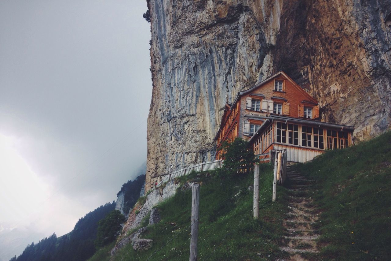 built structure, architecture, building exterior, mountain, house, sky, low angle view, day, nature, steps, outdoors, tree, plant, rock - object, sunlight, no people, railing, residential structure, clear sky, old