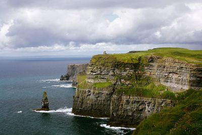 Scenic view of cliff by sea against sky