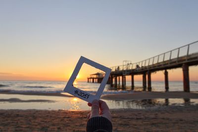 Man and woman on beach against clear sky during sunset