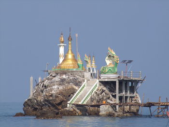 Statue in sea against clear sky