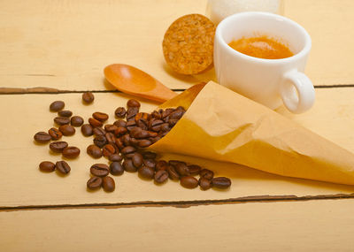 Espresso coffee and beans on a paper cone cornucopia over white background