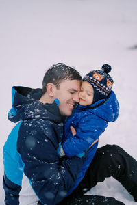 Side view of boy playing with brother on snow