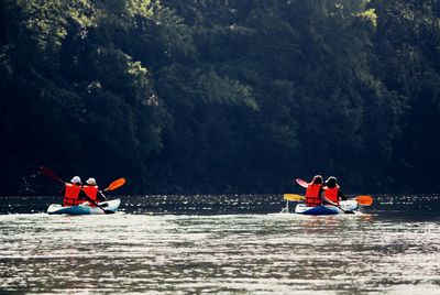 People on boat sailing in river against mountain