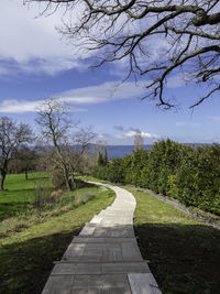 Footpath amidst field against sky