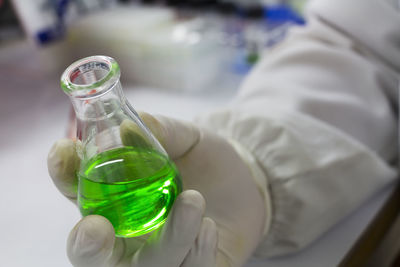 Cropped hand of scientist holding chemical in flask