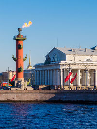 Buildings by sea against clear blue sky