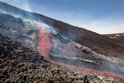 Incancecent lava flow  on etna volcano in sicily in valle del bove with smoke and lava flow canal
