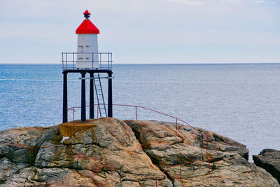 Red railing on a rock with a lighthouse 