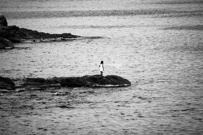 Man on rock in sea