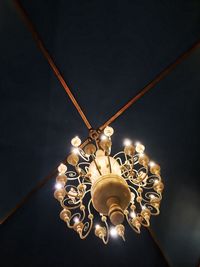 Low angle view of illuminated light bulb hanging on ceiling