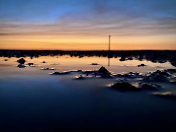 Surface level of sea against sunset sky