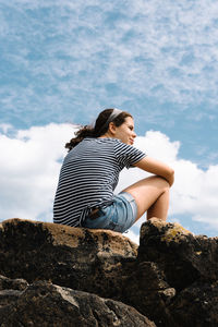 Low angle view of woman sitting on rock