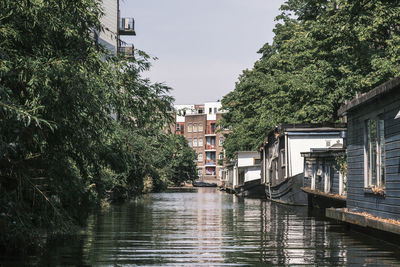 Canal amidst trees and buildings in city