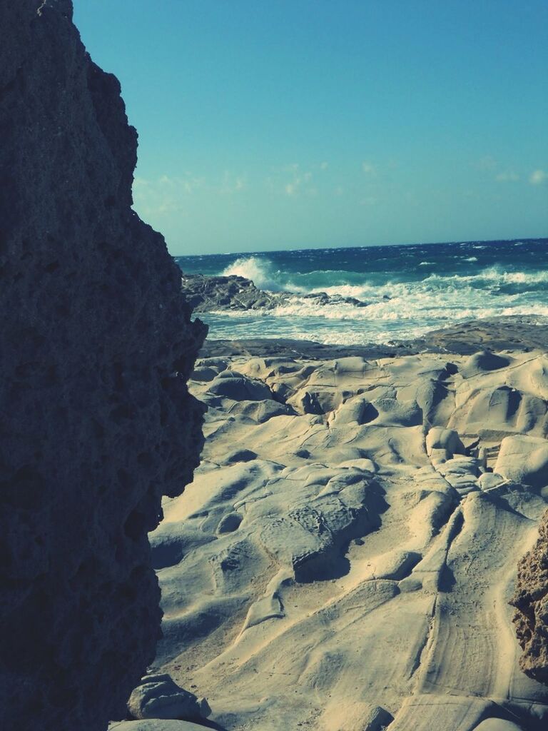 sea, horizon over water, beach, water, scenics, tranquil scene, beauty in nature, tranquility, shore, nature, sky, rock - object, idyllic, sand, clear sky, rock formation, wave, coastline, blue, outdoors