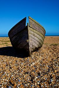 Pebbles on beach against clear blue sky