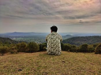 Rear view of man looking at mountain against sky