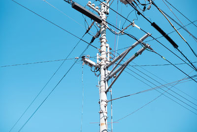 Low angle view of power lines against clear blue sky