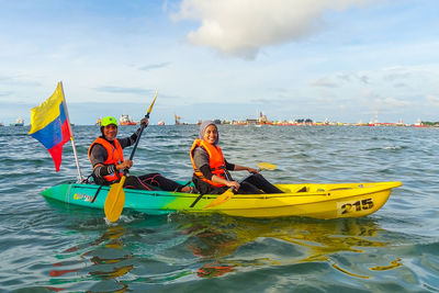 People in boat on sea against sky