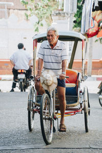 Senior man riding pedicab on road in city