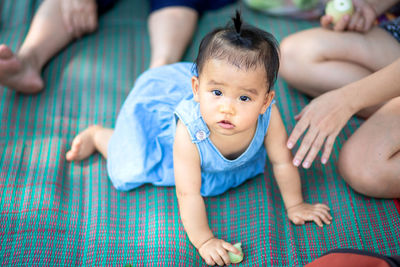 High angle portrait of cute baby girl crawling on mat outdoors