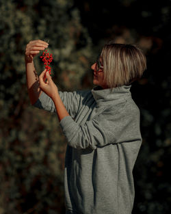 A blonde woman holding ashberries. portrait in the nature.