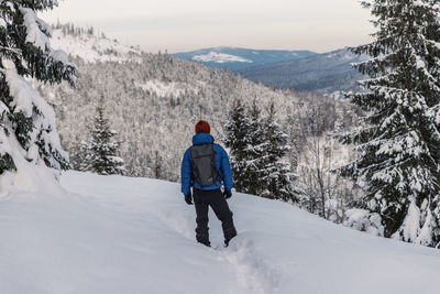 Rear view of man walking on snow covered mountain