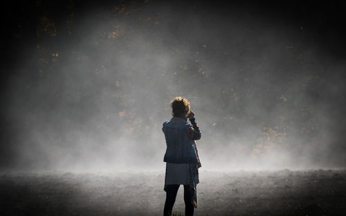 Rear view of woman standing by railing