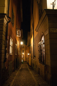 Empty alley amidst buildings at night