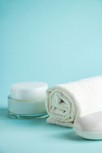 Cosmetic products and spa accessories on blue background. cream, soap and towel. skin care, wellness 