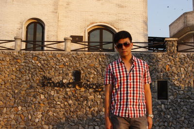 Portrait of young man standing against wall