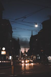 Illuminated city street against sky at night